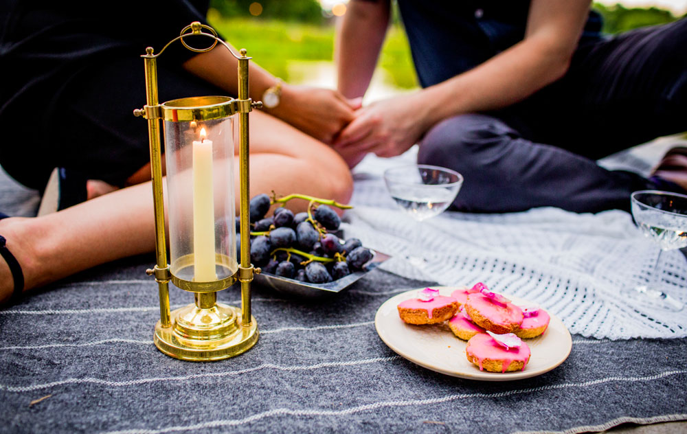 Couple holds hands while having a picnic during their session